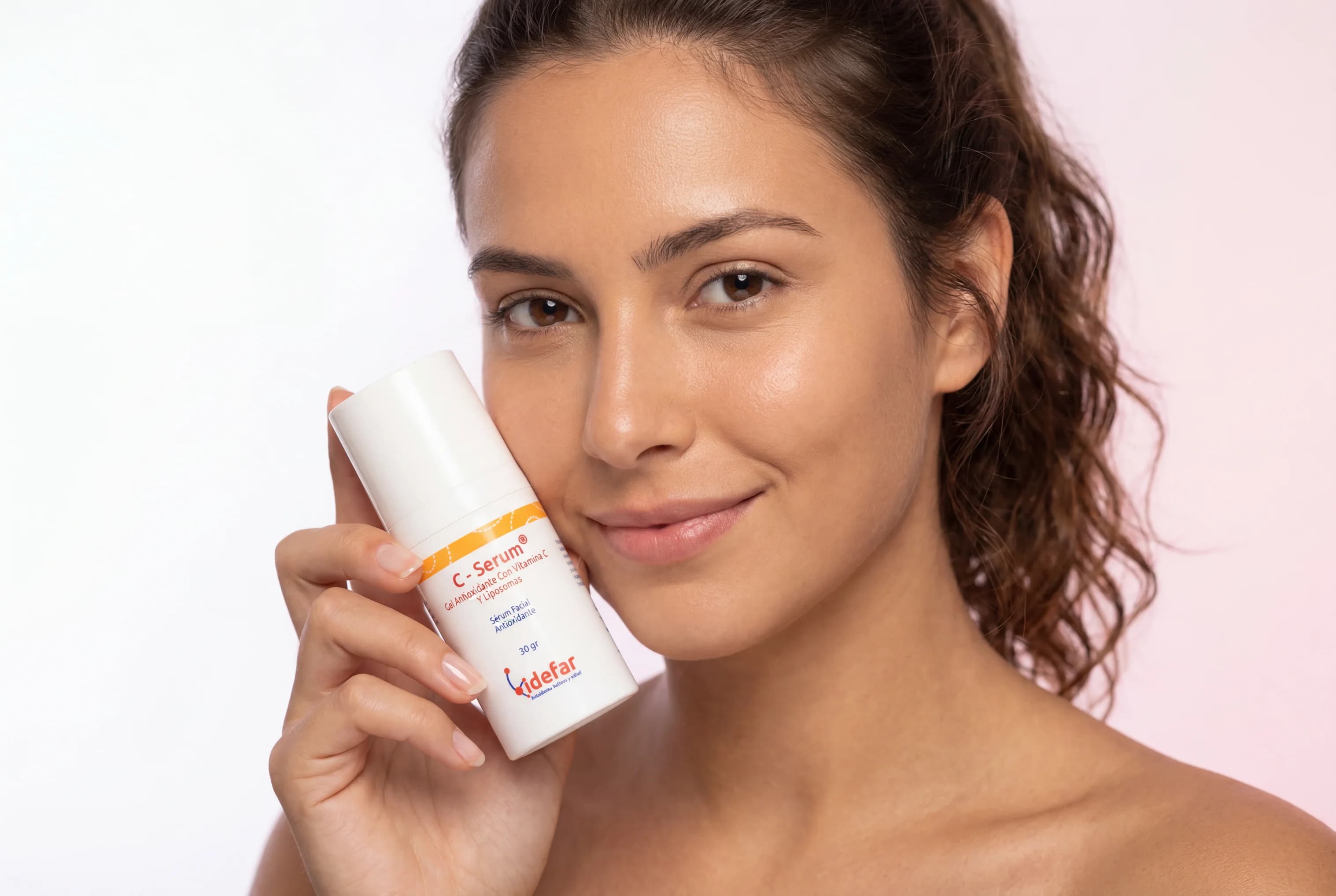 C-Serum Vitamina C — mujer con piel luminosa aplicando gotas del serum
